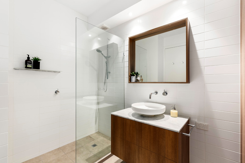 Inspiration for a small contemporary bathroom in Melbourne with flat-panel cabinets, medium wood cabinets, an alcove shower, white tile, ceramic tile, white walls, ceramic floors, a vessel sink, marble benchtops, beige floor and an open shower.