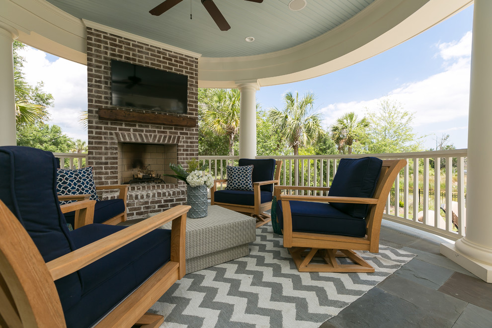 Design ideas for a beach style side yard verandah in Charleston with a fire feature, natural stone pavers and a roof extension.