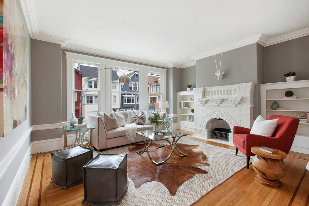 Transitional living room in San Francisco with grey walls, medium hardwood floors, a standard fireplace and no tv.