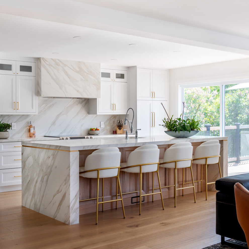 Open concept kitchen - mid-sized transitional galley light wood floor and beige floor open concept kitchen idea in Ottawa with an undermount sink, recessed-panel cabinets, white cabinets, quartz countertops, white backsplash, porcelain backsplash, stainless steel appliances, an island and white countertops