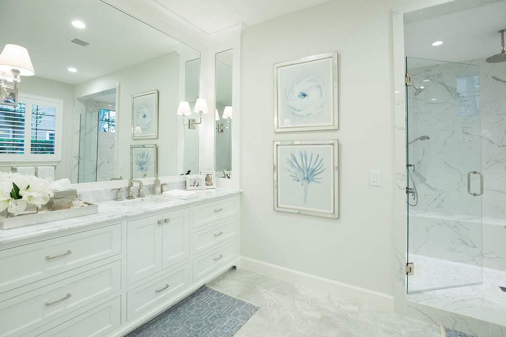 Inspiration for a large traditional master bathroom in Orlando with recessed-panel cabinets, white cabinets, an alcove shower, white tile, marble, beige walls, marble floors, an undermount sink, marble benchtops, grey floor and a hinged shower door.