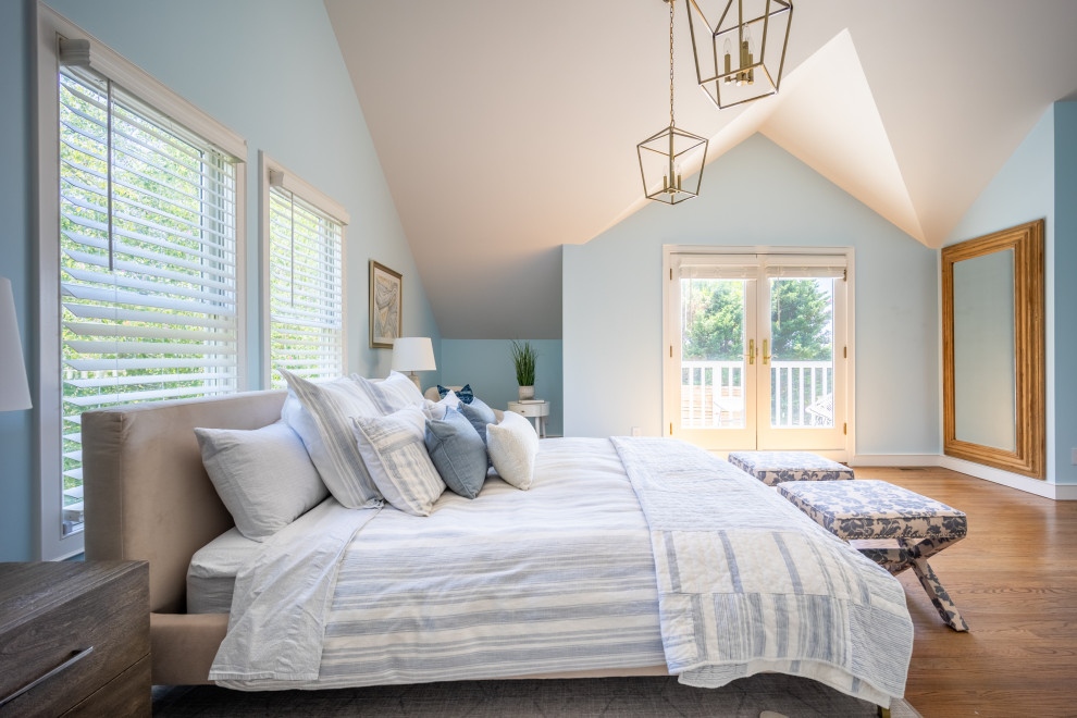 Modelo de dormitorio principal y abovedado marinero grande con paredes azules y suelo de madera en tonos medios