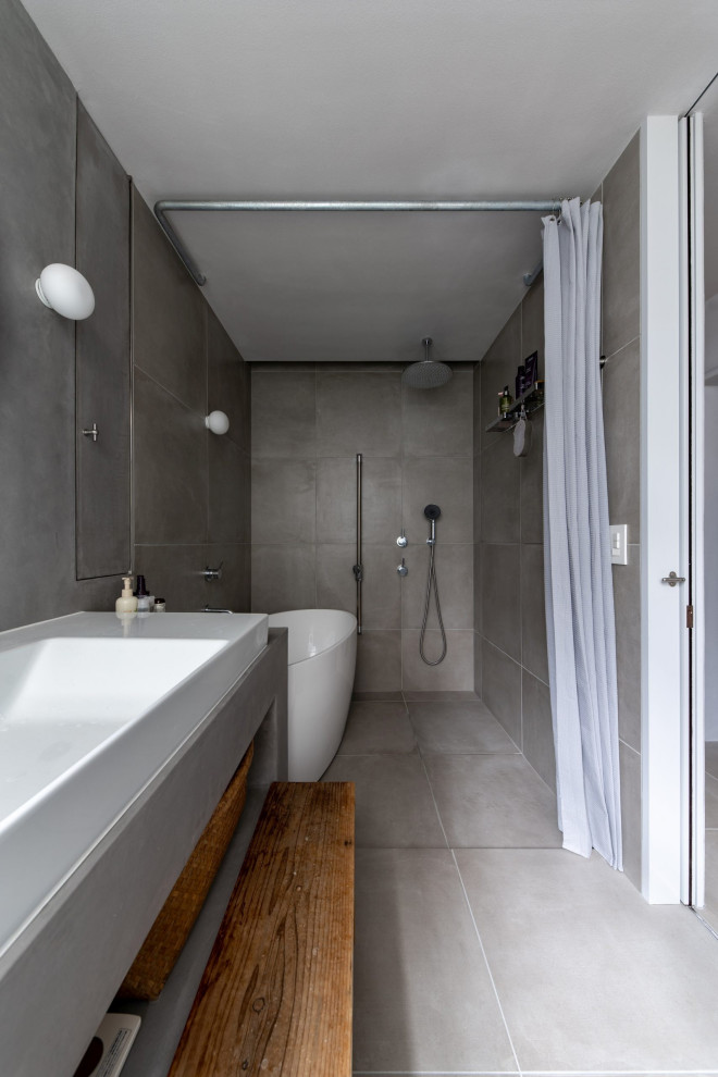 Bild på ett litet skandinaviskt grå grått en-suite badrum, med öppna hyllor, vita skåp, en öppen dusch, grå kakel, porslinskakel, grå väggar, klinkergolv i porslin, grått golv, med dusch som är öppen och ett badkar med tassar