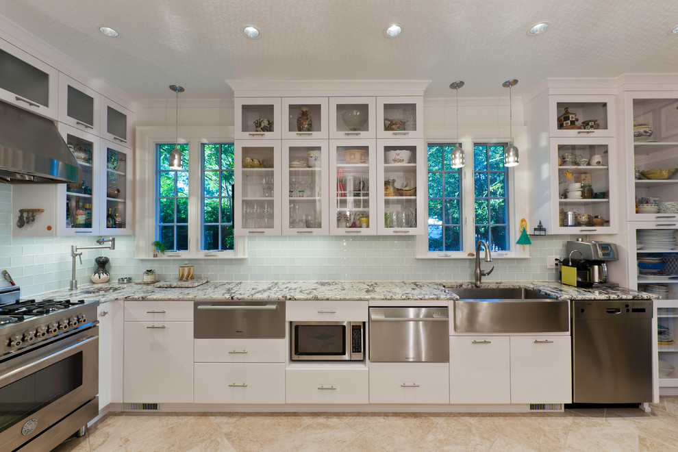 Traditional kitchen in Charlotte with glass-front cabinets, white cabinets, a farmhouse sink, green splashback, glass tile splashback and stainless steel appliances.