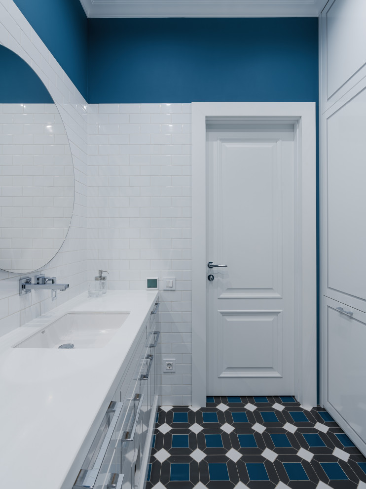 Источник вдохновения для домашнего уюта: детская ванная комната среднего размера с фасадами с утопленной филенкой, белыми фасадами, отдельно стоящей ванной, душем в нише, инсталляцией, белой плиткой, керамической плиткой, синими стенами, полом из керамогранита, врезной раковиной, столешницей из искусственного камня, синим полом, душем с распашными дверями, белой столешницей, гигиеническим душем, тумбой под одну раковину, подвесной тумбой и обоями на стенах