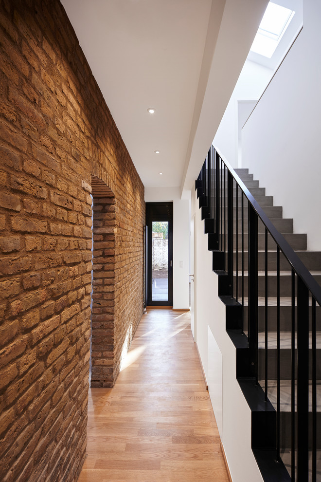 Design ideas for a mid-sized industrial hallway in Frankfurt with white walls, medium hardwood floors and brown floor.