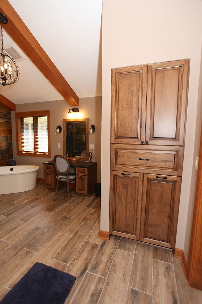 Freestanding bathtub - large rustic master slate tile brown floor freestanding bathtub idea in Indianapolis with brown cabinets, beige walls and an undermount sink
