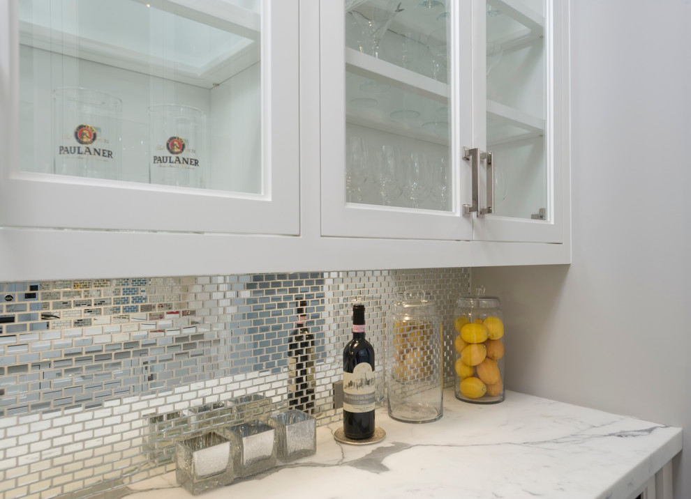 Inspiration for a small transitional galley kitchen pantry in New York with recessed-panel cabinets, white cabinets, an undermount sink, marble benchtops, metallic splashback, mirror splashback, white appliances and marble floors.