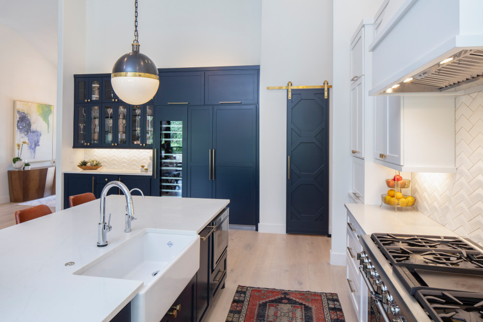 Large transitional u-shaped light wood floor and beige floor eat-in kitchen photo in Austin with a farmhouse sink, recessed-panel cabinets, white cabinets, quartzite countertops, white backsplash, ceramic backsplash, paneled appliances, an island and white countertops