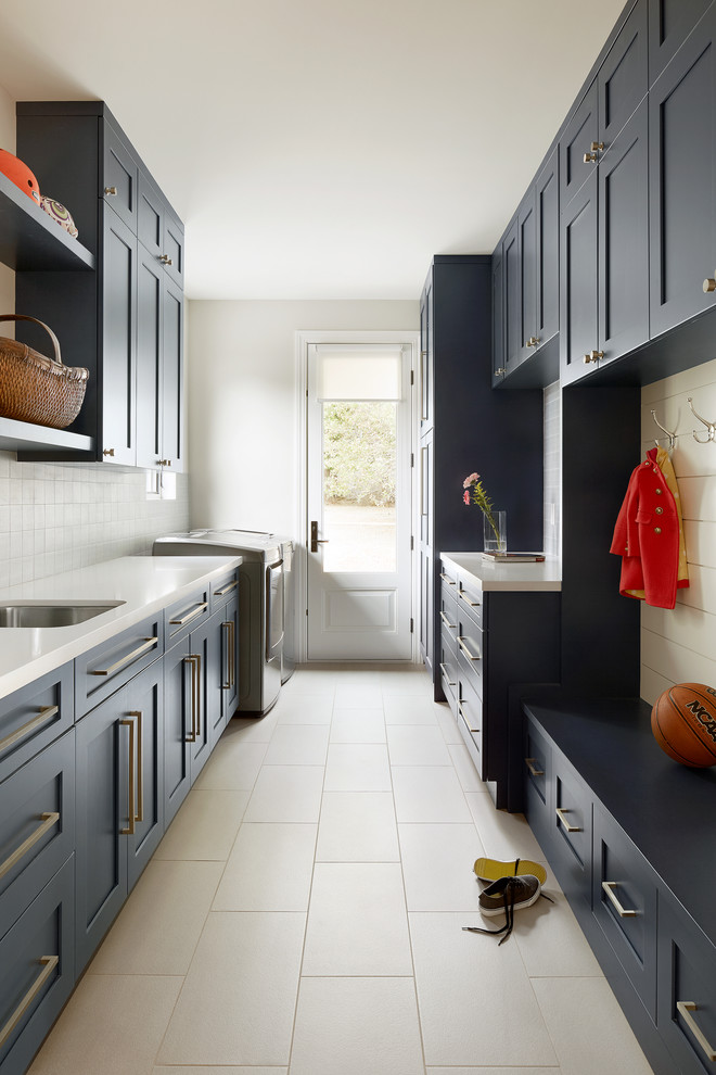 Design ideas for a beach style galley utility room in San Francisco with an undermount sink, shaker cabinets, blue cabinets, grey walls, a side-by-side washer and dryer, beige floor and white benchtop.