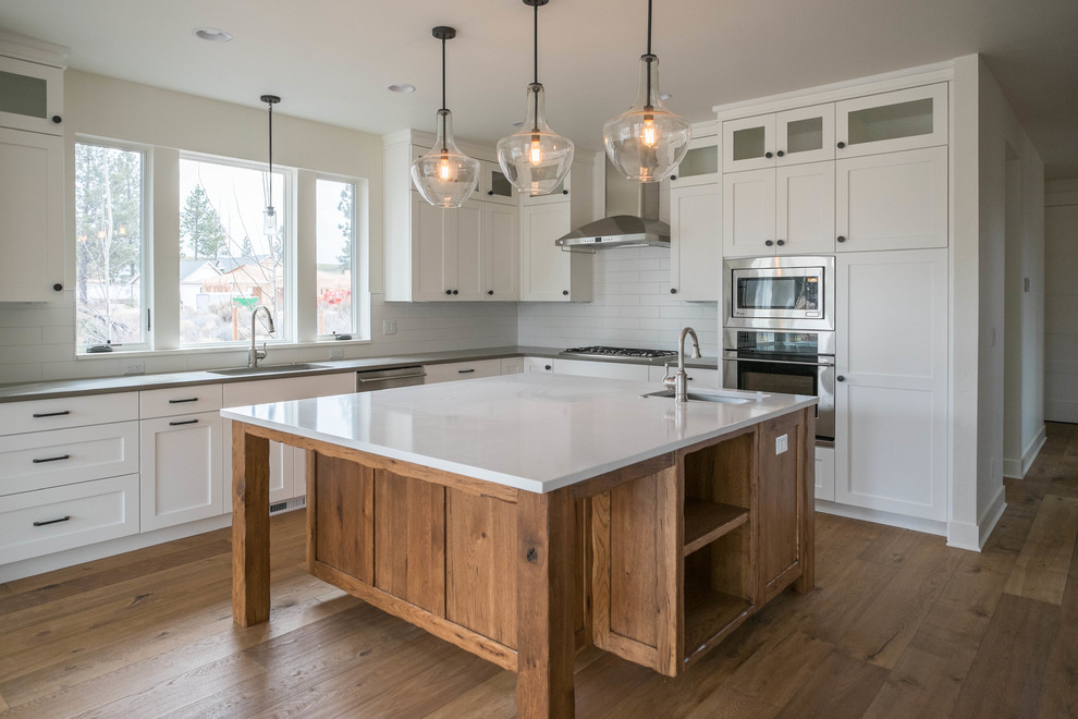 Eat-in kitchen - mid-sized transitional l-shaped medium tone wood floor eat-in kitchen idea with an undermount sink, shaker cabinets, white cabinets, quartz countertops, white backsplash, subway tile backsplash, stainless steel appliances and an island