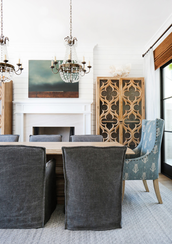 Photo of a mid-sized beach style separate dining room in Orange County with white walls, light hardwood floors and a standard fireplace.