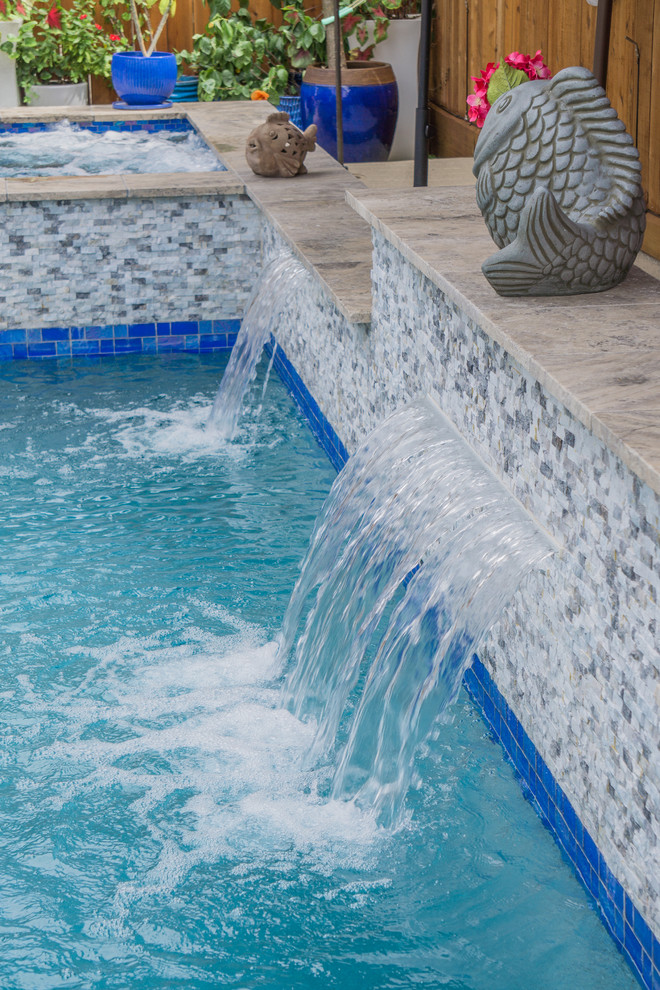 Photo of a small modern backyard rectangular pool in Houston with a water feature and natural stone pavers.