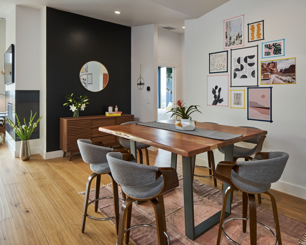 Exemple d'une salle à manger ouverte sur le salon chic de taille moyenne avec un mur noir, un sol en bois brun, cheminée suspendue, un manteau de cheminée en métal, un sol marron et un plafond voûté.