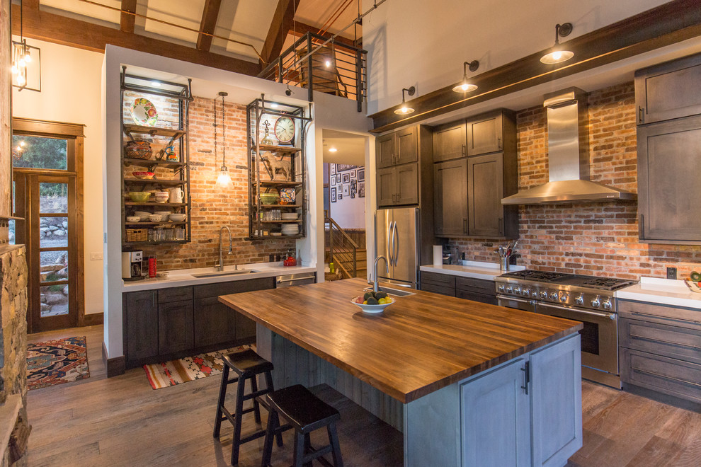Industrial kitchen in Denver with with island, open cabinets, brick splashback, stainless steel appliances, a single-bowl sink and dark hardwood floors.