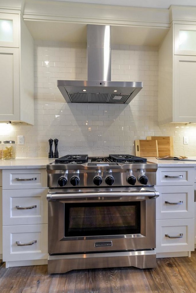 Large transitional u-shaped medium tone wood floor and brown floor open concept kitchen photo in Edmonton with shaker cabinets, quartz countertops, subway tile backsplash, stainless steel appliances, an island, an undermount sink, white cabinets and white backsplash