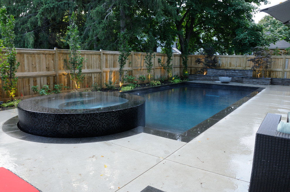 Example of a mid-sized transitional backyard rectangular pool design in Toronto with decking