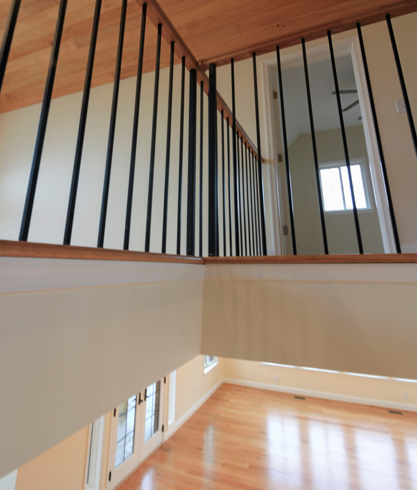 Photo of a large transitional wood floating staircase in DC Metro with wood risers, mixed railing and planked wall panelling.