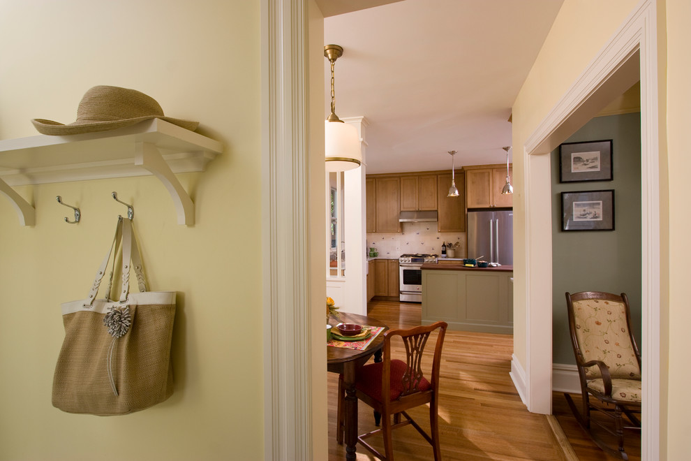 Photo of a mid-sized traditional mudroom in New York with yellow walls, light hardwood floors and a single front door.