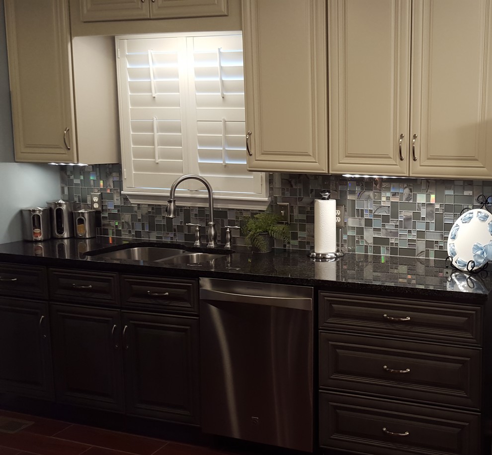 This is an example of a mid-sized transitional galley separate kitchen in Atlanta with an undermount sink, raised-panel cabinets, grey cabinets, granite benchtops, grey splashback, glass tile splashback, stainless steel appliances, porcelain floors and no island.