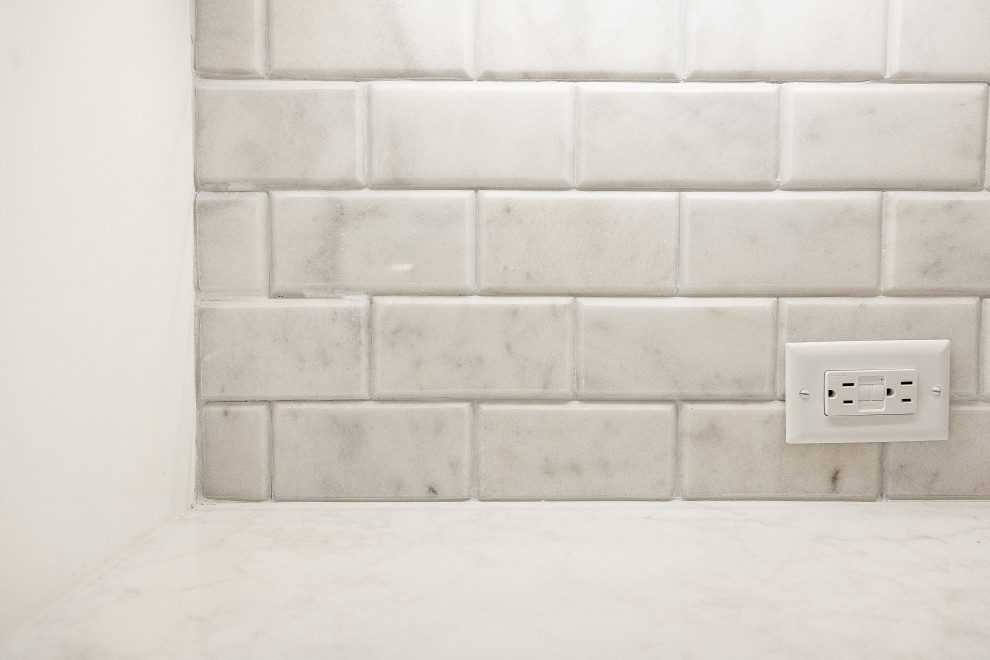 Bild på ett stort funkis vit vitt kök och matrum, med en enkel diskho, luckor med upphöjd panel, vita skåp, bänkskiva i kvarts, grått stänkskydd, stänkskydd i marmor, rostfria vitvaror, mellanmörkt trägolv, en köksö och brunt golv