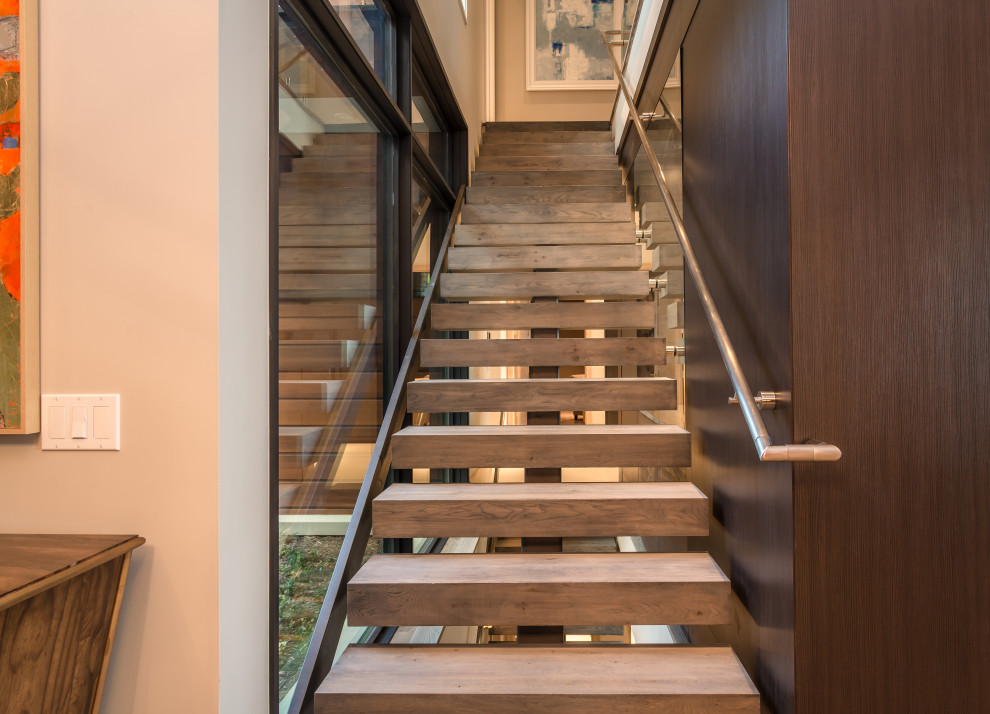 Design ideas for a large modern wood floating staircase in Grand Rapids with metal railing and wood walls.