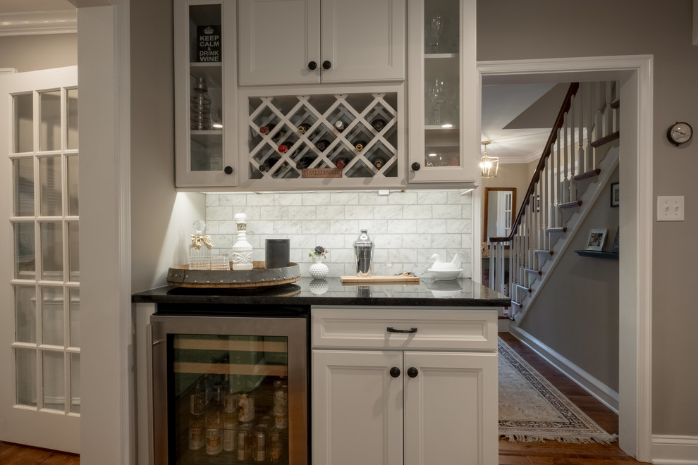 Design ideas for a large country kitchen in Philadelphia with an undermount sink, shaker cabinets, white cabinets, granite benchtops, white splashback, marble splashback, stainless steel appliances, medium hardwood floors, with island, brown floor and black benchtop.