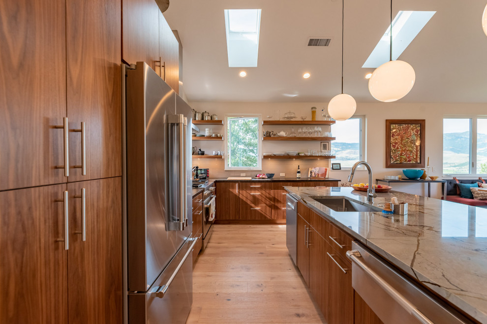 This is an example of a large midcentury l-shaped open plan kitchen in Other with an undermount sink, flat-panel cabinets, medium wood cabinets, granite benchtops, grey splashback, glass tile splashback, stainless steel appliances, light hardwood floors, with island, brown floor, multi-coloured benchtop and vaulted.