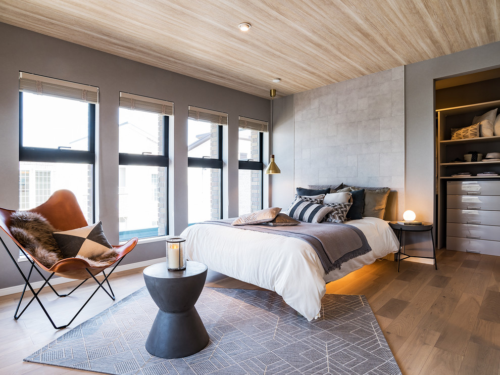 Immagine di una camera da letto tradizionale con pareti grigie, pavimento marrone e pavimento in compensato