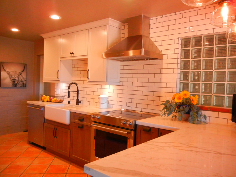 Photo of a mid-sized country u-shaped eat-in kitchen in Orange County with a farmhouse sink, shaker cabinets, white cabinets, quartz benchtops, white splashback, ceramic splashback, stainless steel appliances, ceramic floors, no island, multi-coloured floor and white benchtop.