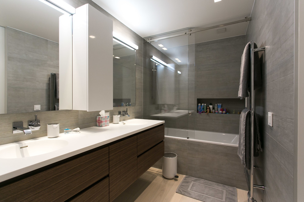 Photo of a contemporary 3/4 bathroom in Milan with flat-panel cabinets, brown cabinets, a drop-in tub, a shower/bathtub combo, gray tile, an integrated sink, beige floor and a sliding shower screen.