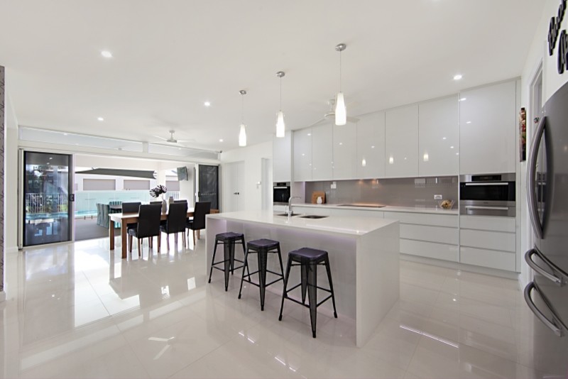 Inspiration for a large modern galley eat-in kitchen in Townsville with a drop-in sink, white cabinets, quartz benchtops, brown splashback, glass sheet splashback, stainless steel appliances, porcelain floors and with island.