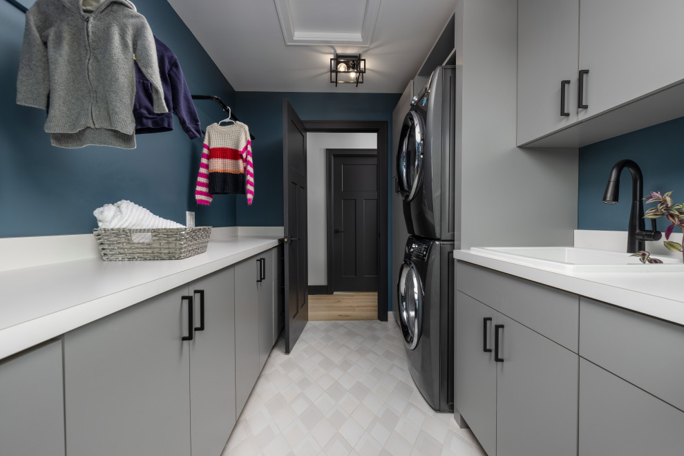 Foto di una lavanderia minimalista con pareti bianche, lavatrice e asciugatrice affiancate, pavimento multicolore e top bianco