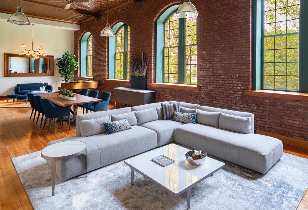Expansive industrial open concept living room in New York with white walls and light hardwood floors.
