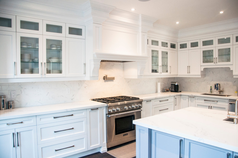 Large transitional l-shaped dark wood floor and brown floor enclosed kitchen photo in Toronto with an undermount sink, shaker cabinets, white cabinets, quartz countertops, white backsplash, marble backsplash, stainless steel appliances, an island and white countertops