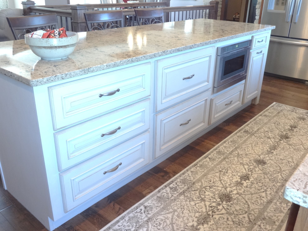 Large single-wall open concept kitchen photo with an undermount sink, raised-panel cabinets, medium tone wood cabinets, quartzite countertops, stainless steel appliances and an island
