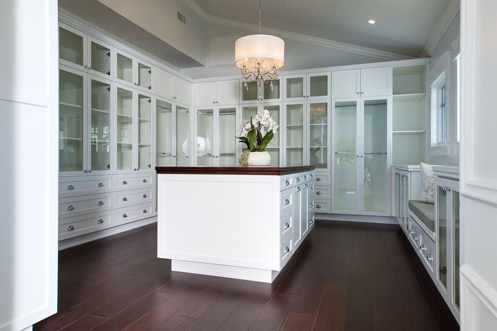 Huge beach style gender-neutral dark wood floor walk-in closet photo in Los Angeles with glass-front cabinets and white cabinets