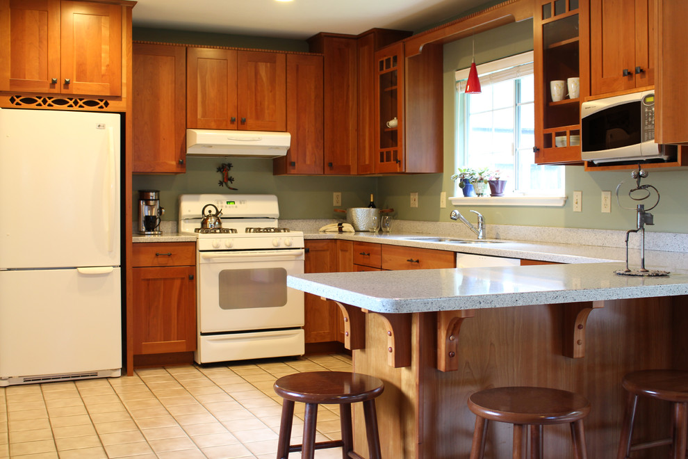 Photo of a mid-sized arts and crafts u-shaped eat-in kitchen in Other with an undermount sink, shaker cabinets, medium wood cabinets, solid surface benchtops, multi-coloured splashback, white appliances, ceramic floors, a peninsula and white floor.