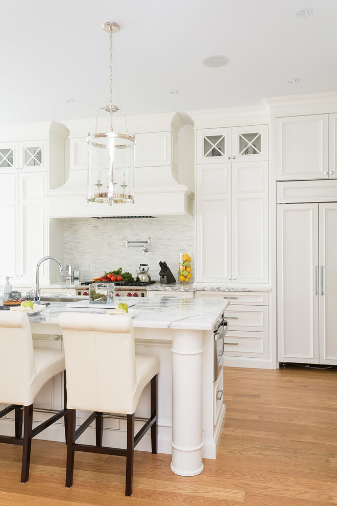 Inspiration for a traditional kitchen in Toronto with white cabinets, marble benchtops, white splashback, panelled appliances and light hardwood floors.