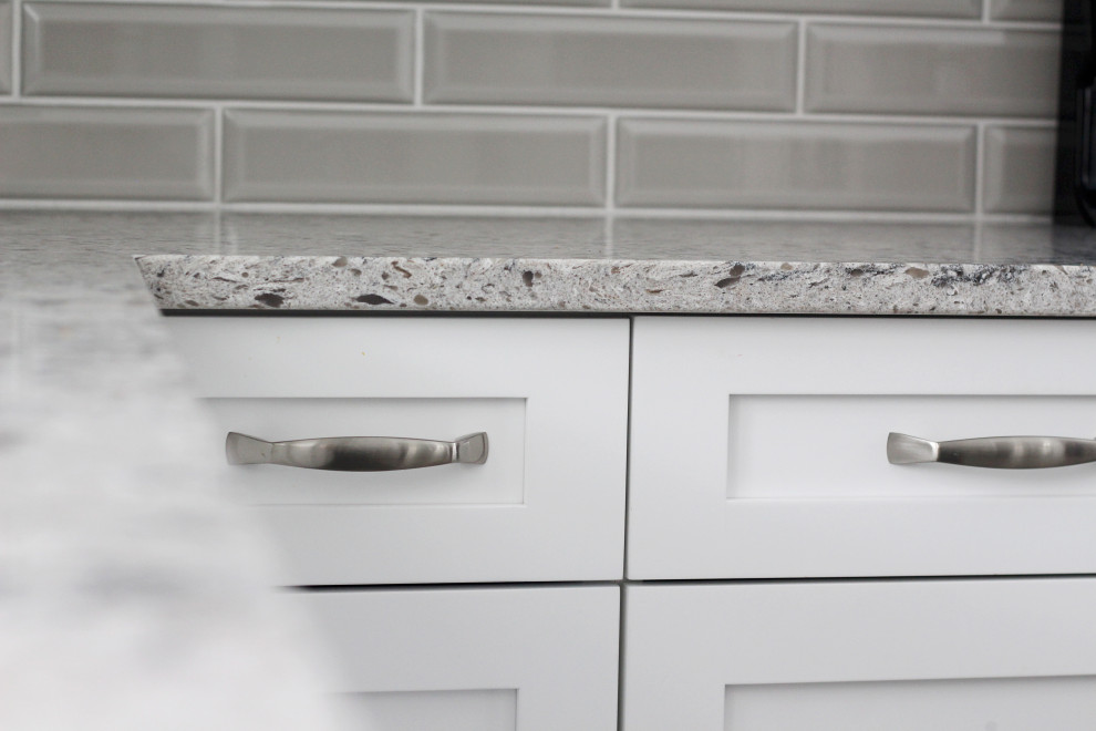 Example of an u-shaped kitchen design with shaker cabinets, white cabinets, quartzite countertops, gray backsplash, subway tile backsplash, a peninsula and gray countertops