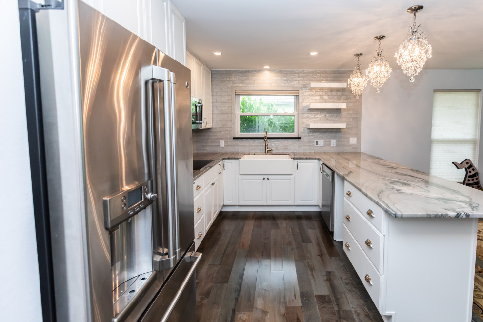 Photo of a medium sized classic u-shaped kitchen/diner with white cabinets and stainless steel appliances.