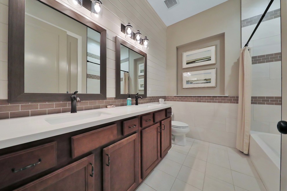 Inspiration for a mid-sized country bathroom in Jacksonville with raised-panel cabinets, medium wood cabinets, a drop-in tub, ceramic floors, an undermount sink, engineered quartz benchtops and beige floor.
