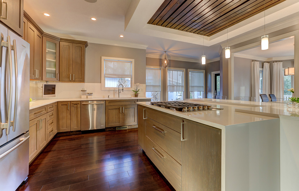 Example of a transitional dark wood floor kitchen design with an undermount sink, gray cabinets, quartzite countertops, white backsplash, porcelain backsplash, stainless steel appliances and an island