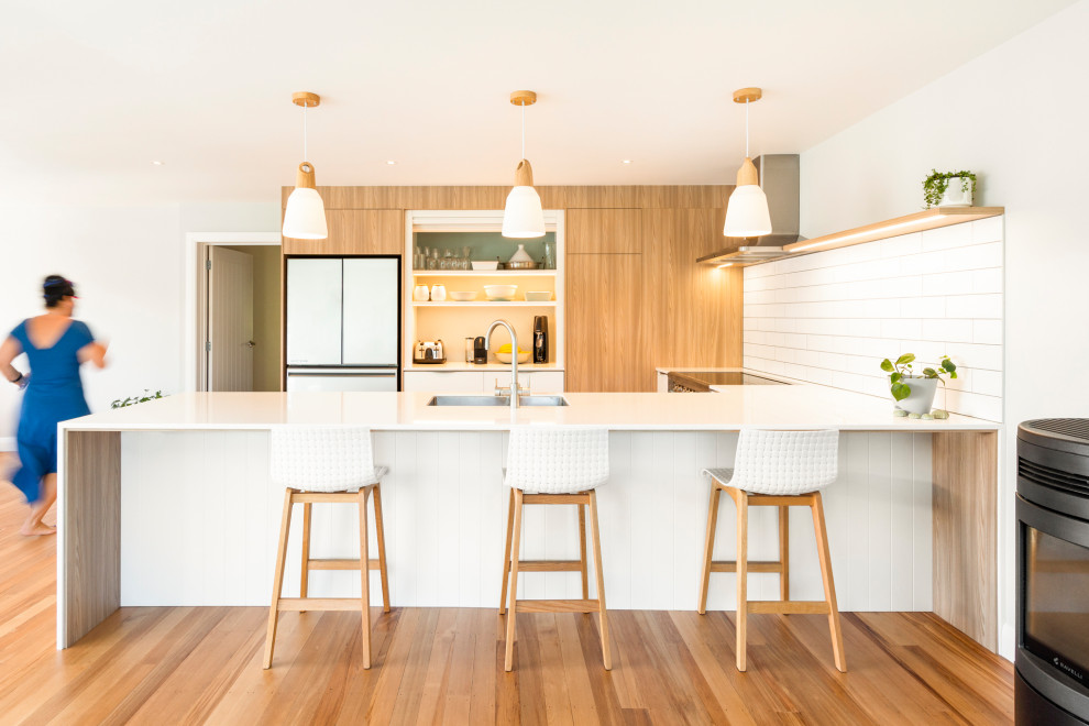 Design ideas for a contemporary U-shaped kitchen With an Undermount Sink, Flat-panel Cabinets, Medium Wood Cabinets, White Splashback, Stainless Steel Appliances, Medium Hardwood Floors, a Peninsula, Brown Floor and White Benchtop.