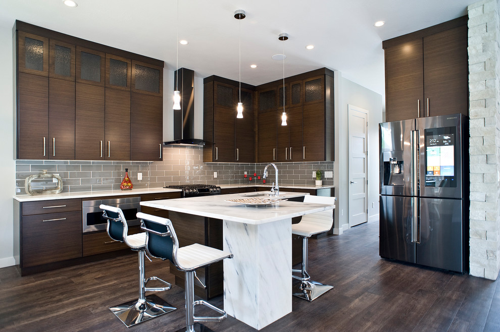 Eat-in kitchen - mid-sized transitional l-shaped medium tone wood floor and brown floor eat-in kitchen idea with an undermount sink, flat-panel cabinets, dark wood cabinets, marble countertops, gray backsplash, subway tile backsplash, stainless steel appliances and an island