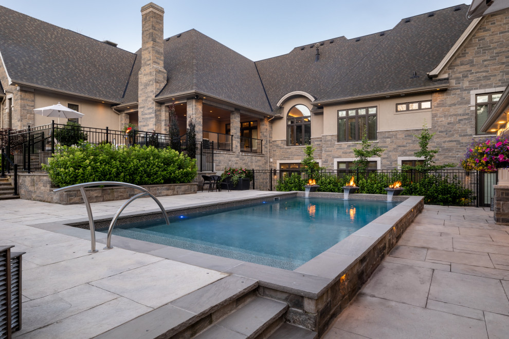 Example of a mid-sized transitional backyard stamped concrete and rectangular pool landscaping design in Toronto
