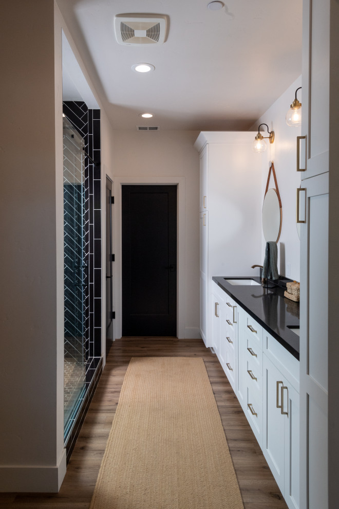 Foto de cuarto de baño abovedado campestre grande con armarios estilo shaker, puertas de armario negras, suelo de madera clara y suelo marrón