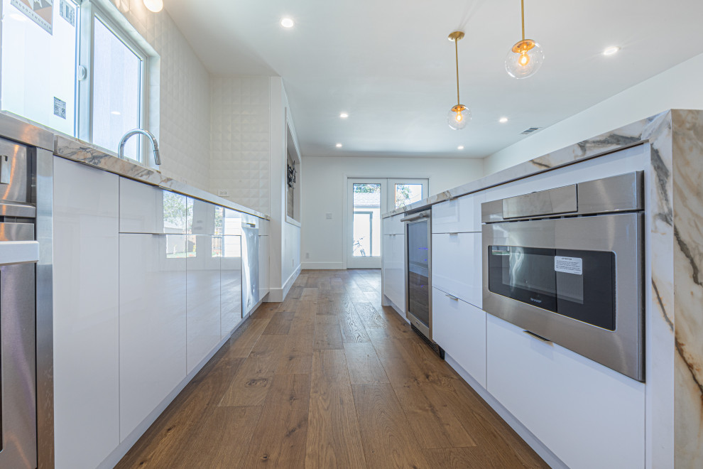 Foto på ett funkis flerfärgad kök och matrum, med en undermonterad diskho, släta luckor, vita skåp, marmorbänkskiva, vitt stänkskydd, stänkskydd i mosaik, vita vitvaror, målat trägolv, en köksö och beiget golv