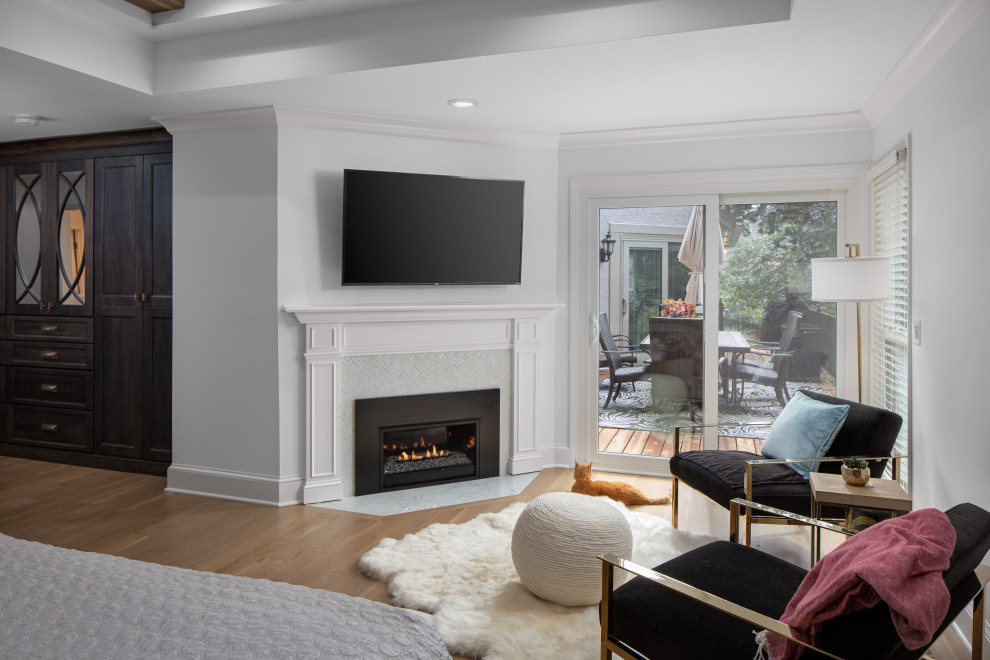 Design ideas for a large transitional master bedroom in Kansas City with white walls, light hardwood floors, a standard fireplace, a tile fireplace surround and timber.