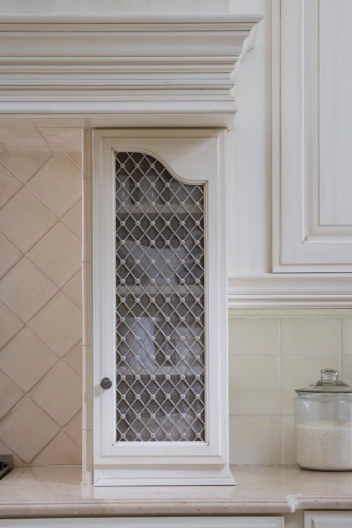 Eat-in kitchen - mid-sized transitional l-shaped travertine floor eat-in kitchen idea in Chicago with a farmhouse sink, raised-panel cabinets, white backsplash, paneled appliances, an island, white cabinets, quartz countertops and porcelain backsplash